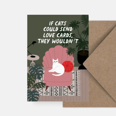 Cartão com gato branco numa cadeira rosa, plantas e texto em inglês, envelope castanho ao lado