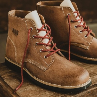 Botas masculinas em camurça castanha com atacadores vermelhos sobre caixa de madeira