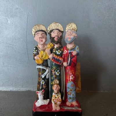 Figura decorativa colorida de três personagens com halos e as suas figuras menores