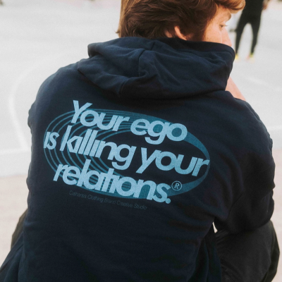 Camisola azul escura com texto azul claro nas costas e pessoa sentada em espaço aberto