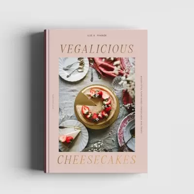 Livro VEGALICIOUS CHEESECAKES com imagem de cheesecake e decoração em mesa