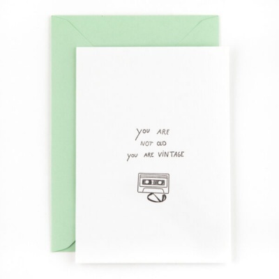 Cartão branco com envelope verde e ilustração de cassete com texto motivacional