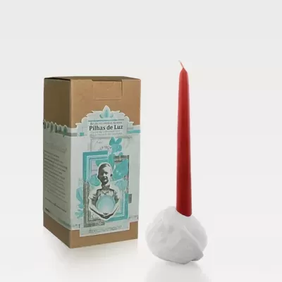 Vela vermelha com suporte branco junto a caixa de cartão com etiqueta decorativa