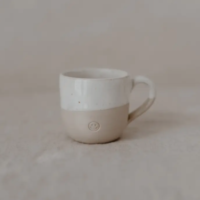 Caneca de cerâmica branca com base bege e símbolo círculo gravado