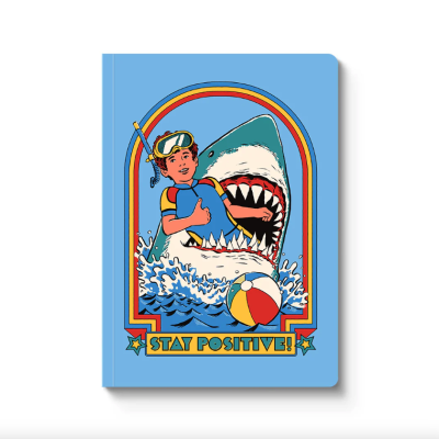 Caderno azul com ilustração de menino, tubarão e texto STAY POSITIVE!