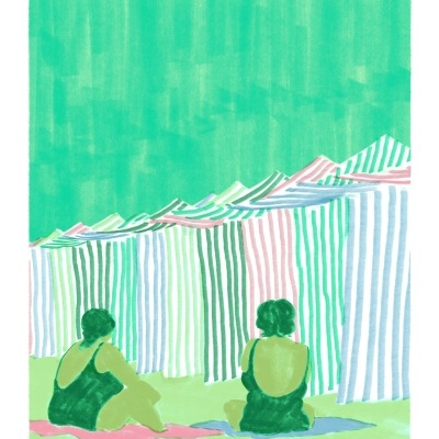 Duas pessoas sentadas de costas em toalhas com cabines listradas ao fundo