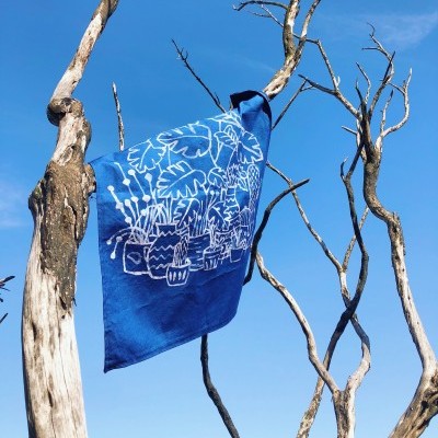 Pano azul com padrão branco de plantas pendurado em árvore seca