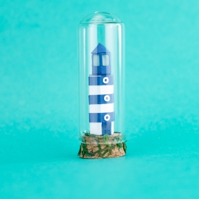 Miniatura de farol azul e branco em base de cortiça e vidro transparente