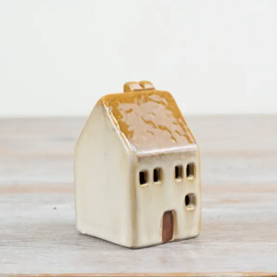 Pequena casa decorativa de cerâmica bege com tecto castanho em superfície de madeira