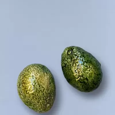 Dois objetos verdes com textura que se assemelham a abacates sobre fundo cinzento