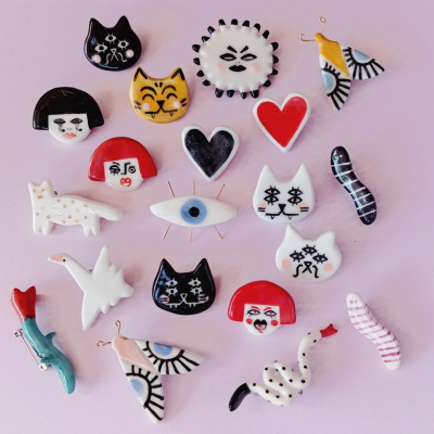 Pins decorativos variados em cerâmica sobre fundo rosa