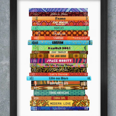 Quadro com moldura preta com uma pilha de livros coloridos com títulos em inglês