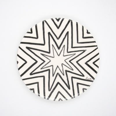 Prato cerâmico redondo branco com padrão geométrico preto em estrela.