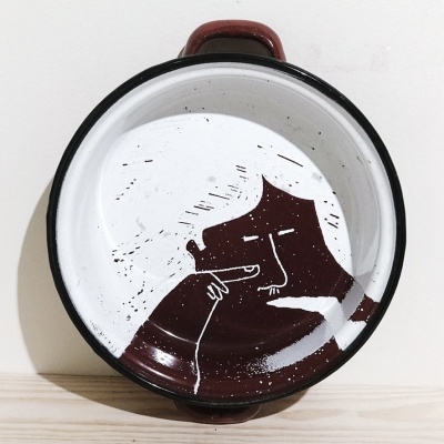 Panela esmaltada branca e castanha com desenho de rosto humano