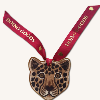 Etiqueta decorativa em forma de cabeça de onça com fita vermelha e texto dourado