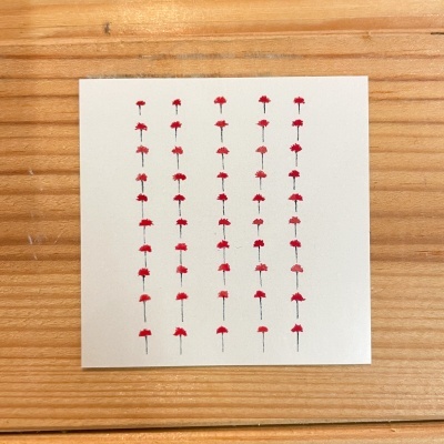 Cartão branco com padrão de flores vermelhas em linhas verticais sobre madeira