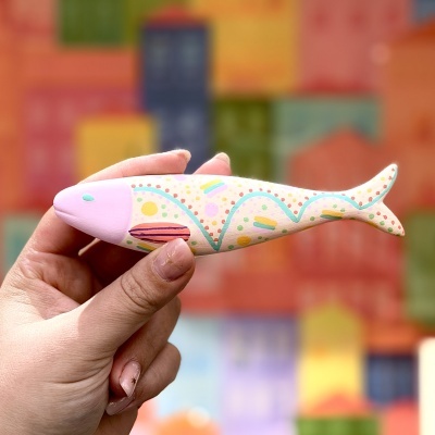 Peixe decorativo de cerâmica colorido segurado por mão