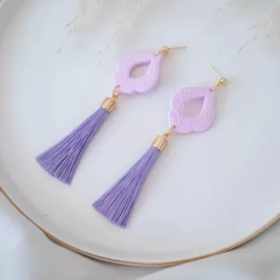 Brincos com franjas roxas e base lilás clara texturizada em forma de losango