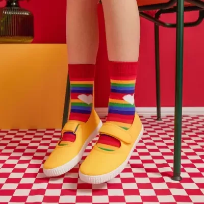 Sapatilhas amarelas com meias riscas coloridas e chão quadriculado vermelho e branco
