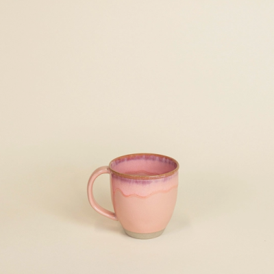 Caneca de cerâmica rosa com interior lilás sobre fundo bege