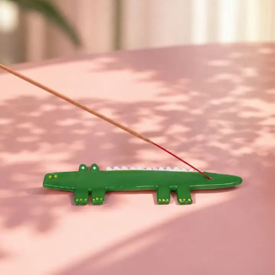 Suporte para incenso em forma de crocodilo verde sobre superfície rosa