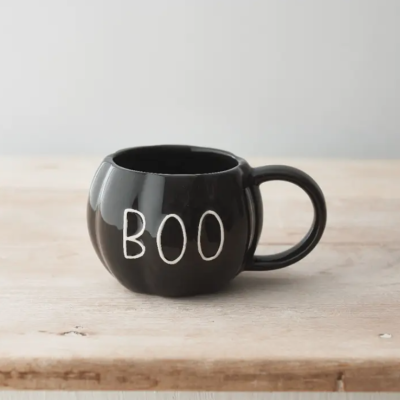 Caneca preta com a palavra BOO em branco numa mesa de madeira