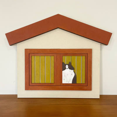 Quadro decorativo em forma de casa com moldura castanha, janelas amarelas e desenho de cão preto e branco