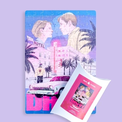 Puzzle ilustrado com duas personagens e um carro antigo cor-de-rosa, com estojo branco e rosa em cima