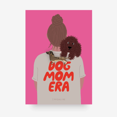 Pessoa de costas com t-shirt bege com texto vermelho DOG MOM ERA e cachorro castanho no ombro, fundo rosa