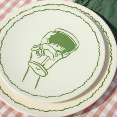 Dois pratos de cerâmica branca com detalhes verdes sobre toalha xadrez rosa e branca