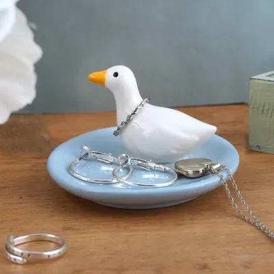 anel e brincos de prata com figura decorativa de cerâmica em forma de pato num prato azul