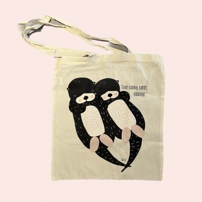 Saco de tecido bege com estampa de duas lontras e texto.