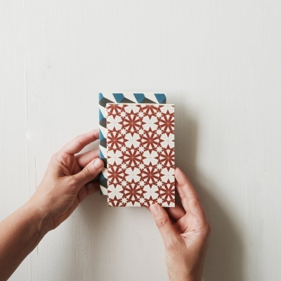 Duas capas de cadernos com padrões geométricos seguradas por mãos