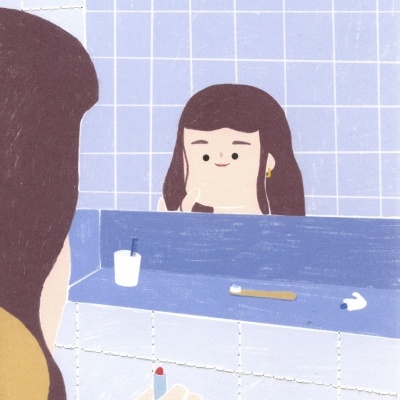 Casa de banho com azulejos azuis e espelho mostrando mulher e artigos pessoais