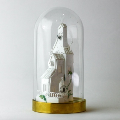 Figura decorativa branca de casa com torre dentro de campânula de vidro
