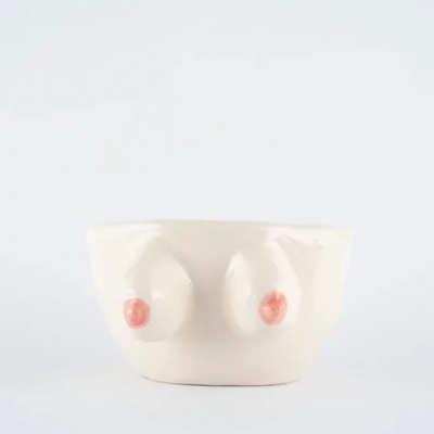 Taça de cerâmica branca com relevo de seios coloridos em vermelho e rosa.