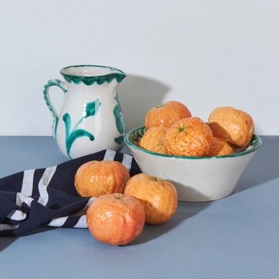 Vaso e tigela com tangerinas sobre superfície azul com pano