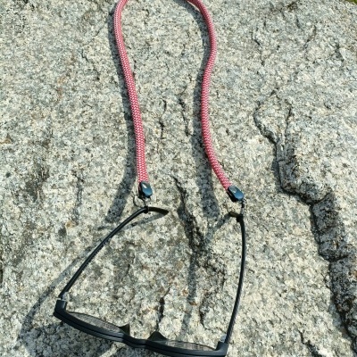 Óculos de sol com cordão rosa sobre pedra