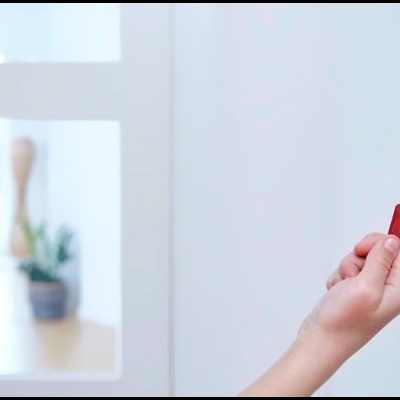 Pessoa a usar cartão vermelho para aceder a teclado digital branco na parede