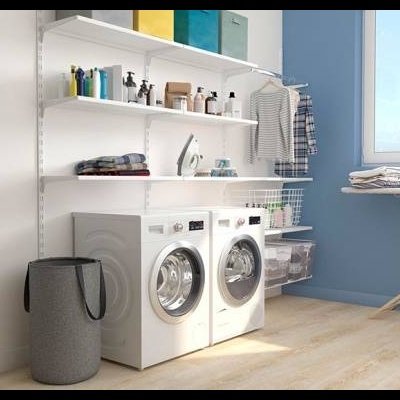 Lavandaria com duas máquinas de lavar lado a lado, prateleiras com produtos e roupa pendurada