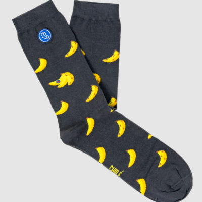 Meias pretas com padrão de bananas amarelas, uma banana com olhos e boca, logo azul e texto CHINÉ.