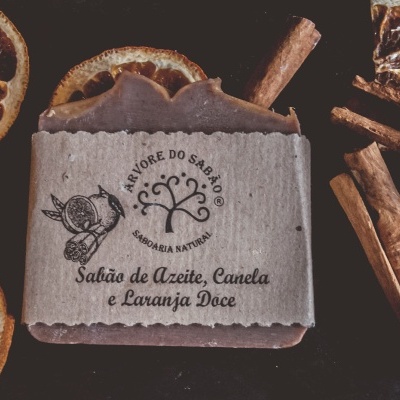Sabão natural de azeite, canela e laranja doce com embalagem de papel e elementos naturais ao redor.
