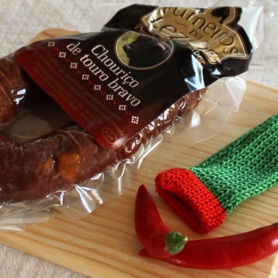 Chouriço embalado com malaguetas e proteção tricotada na tábua de madeira