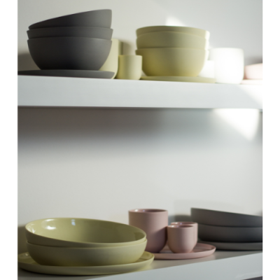 Conjuntos de loiça em tons pastel organizados em prateleiras brancas