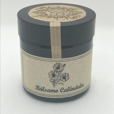 Frasco preto com rótulo bege de bálsamo de calêndula com ilustrações de flores