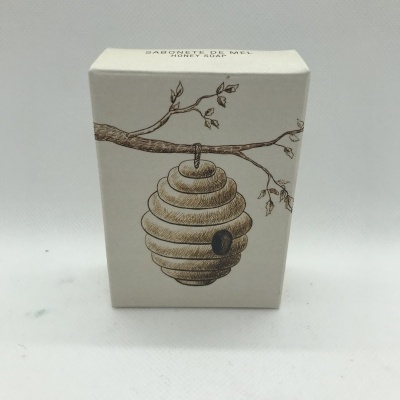 Caixa bege com desenho de colmeia pendurada num ramo