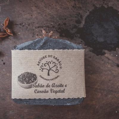 Sabão artesanal com embalagem de papel reciclado e texto em português sobre madeira com anis e carvão.