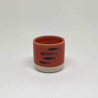 Copo de cerâmica laranja com desenhos de peixes azuis