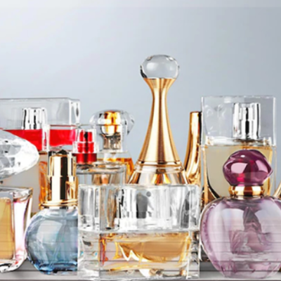 Frascos de perfume coloridos de vidro em uma superfície clara com fundo cinzento.