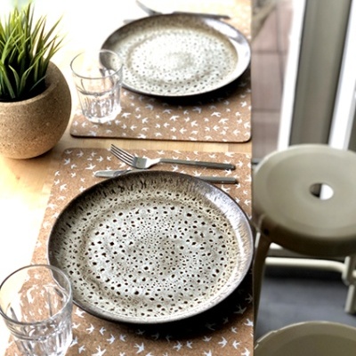 Mesa posta com pratos de cerâmica e copos em ambiente iluminado